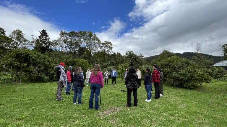 Grupo en círculo sobre el pasto con las montañas al fondo