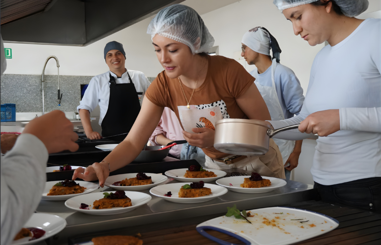 Participantes emplatan un postre con frutos rojos en la cocina
