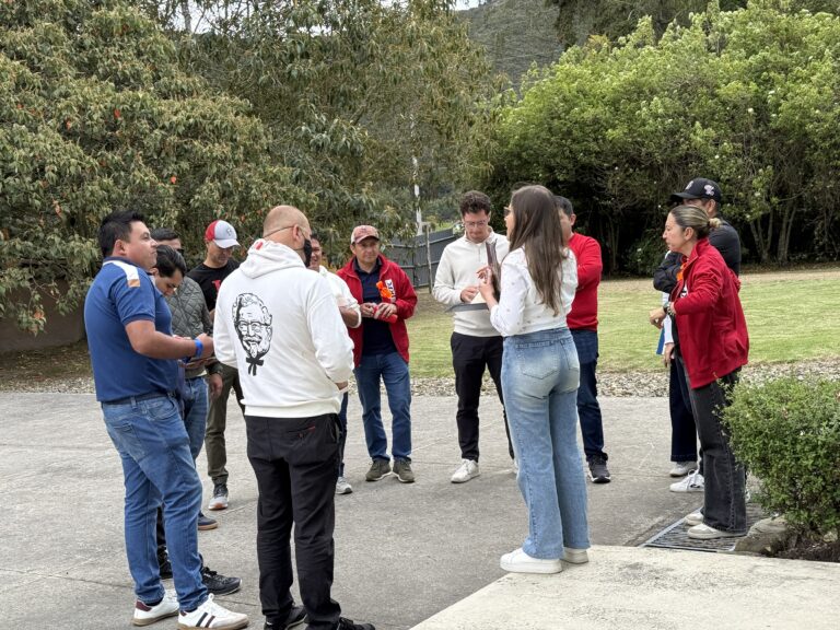 Equipo de trabajo escucha a una facilitadora antes de una actividad