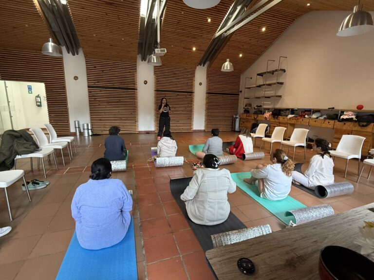 Salón de techo en madera con participantes en tapetes de yoga